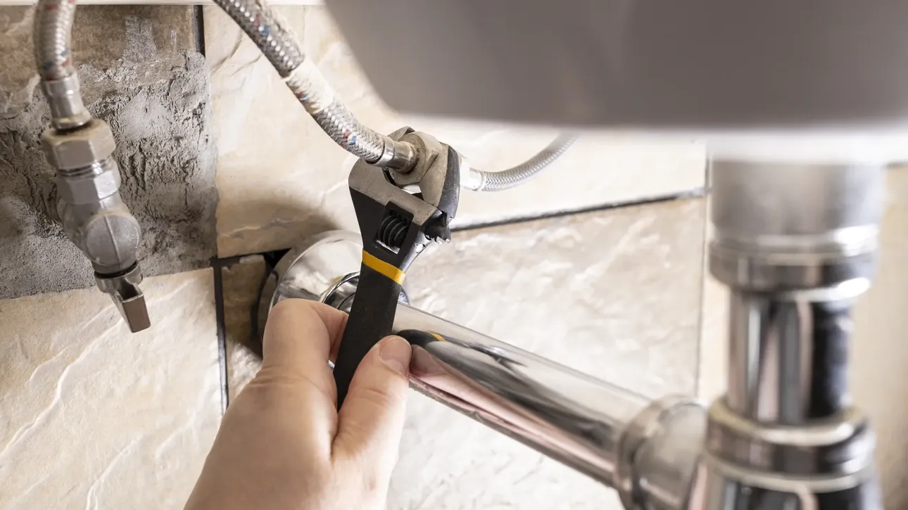 Home inspector checking plumbing under kitchen sink during Texas home inspection before closing